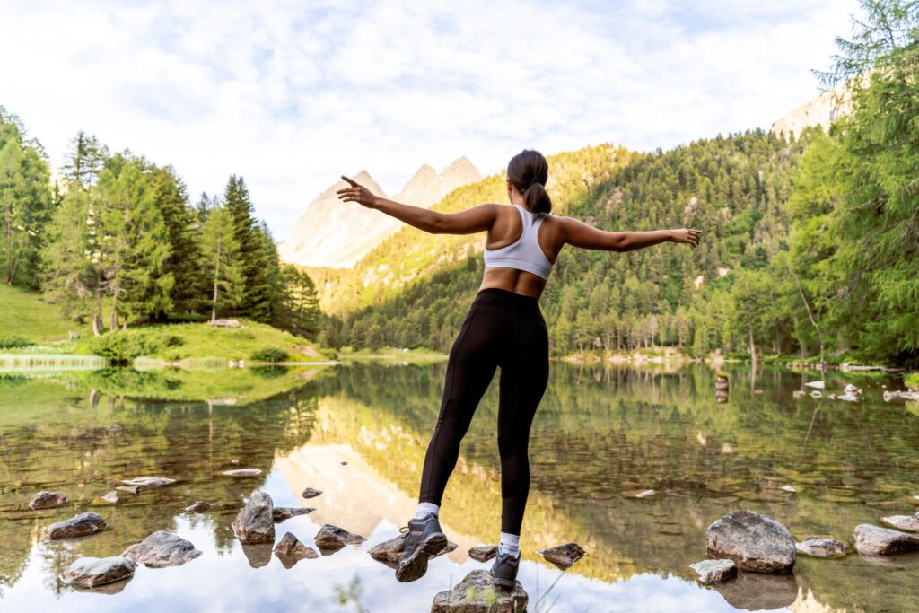 Woman standing on a mountain overlook at sunrise, representing balance, alignment, mobility, and overall wellness through the A.S.A.P. (Assisted Self Alignment Protocol) approach.