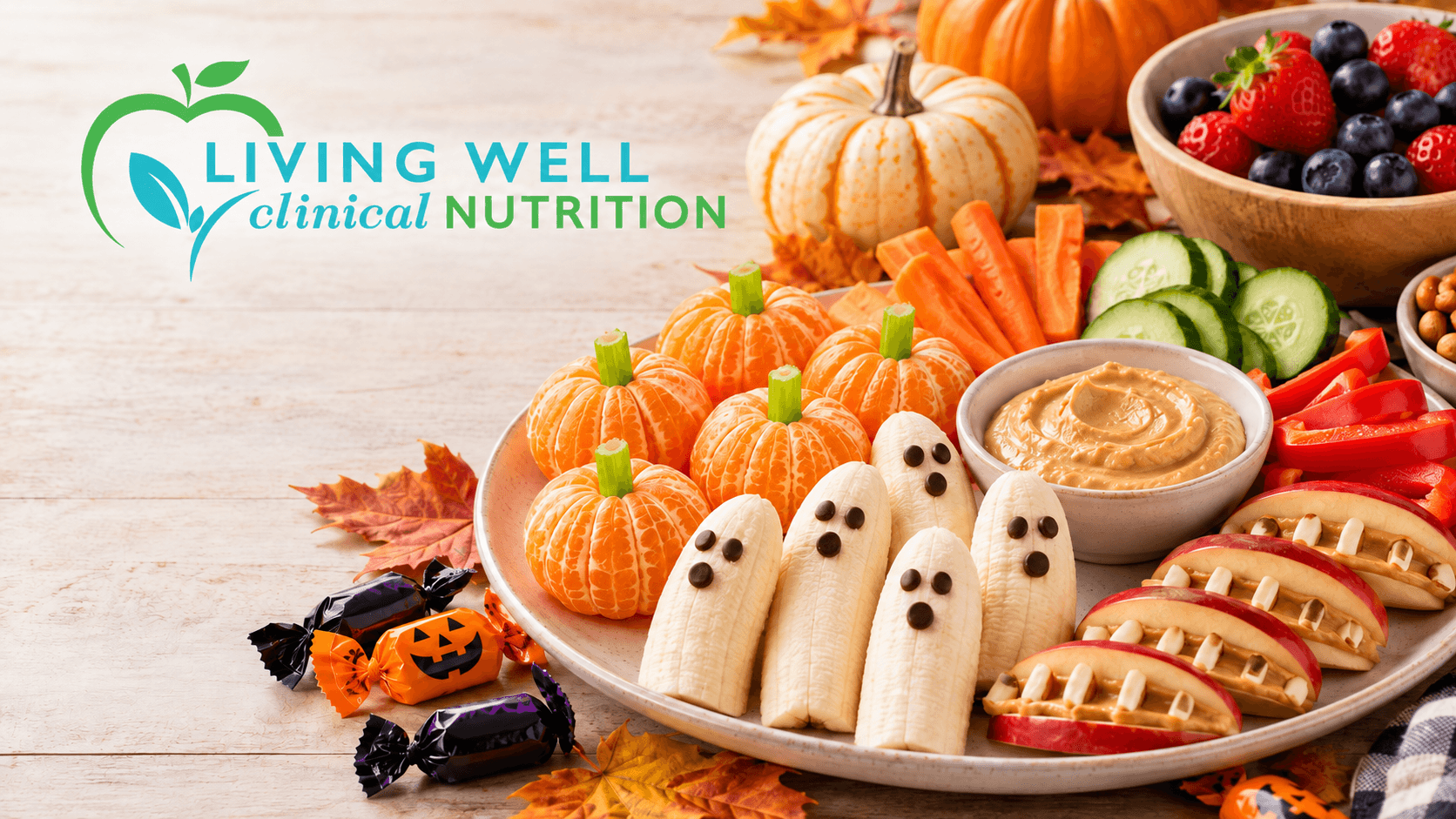Healthy Halloween snacks with mandarin pumpkins, banana ghosts, fresh vegetables, hummus, and fall decorations